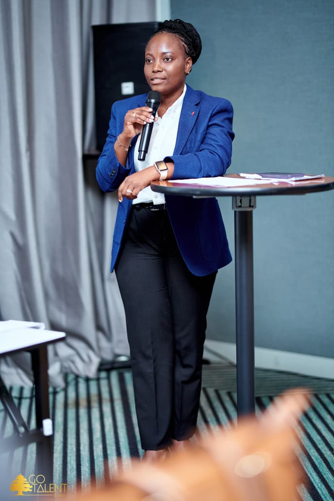 Me Benita Tshibola au micro lors de la rencontre L’humain au centre, en décembre 2025