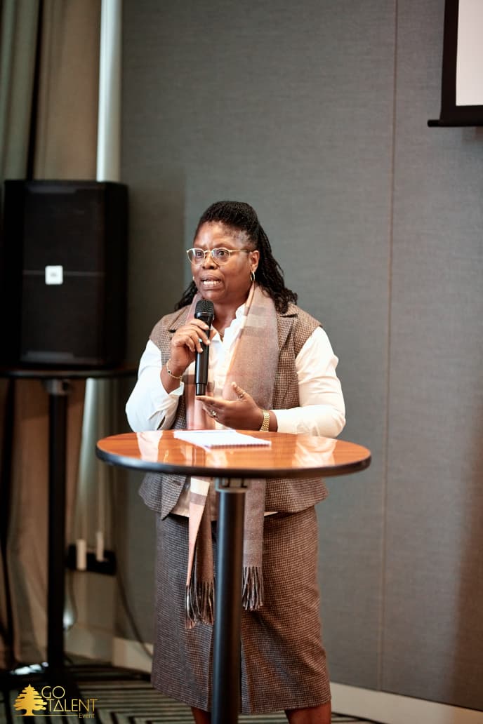 Mme Nelly Tshela au micro lors de la rencontre L’humain au centre, en décembre 2025
